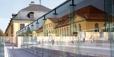 Außenansicht des Arne-Jacobsen-Foyers, in der Spiegelung die Orangerie sichtbar