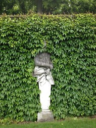 Steinfigur einer Frau, halb verdeckt durch Efeu, in den Herrenhäuser Gärten